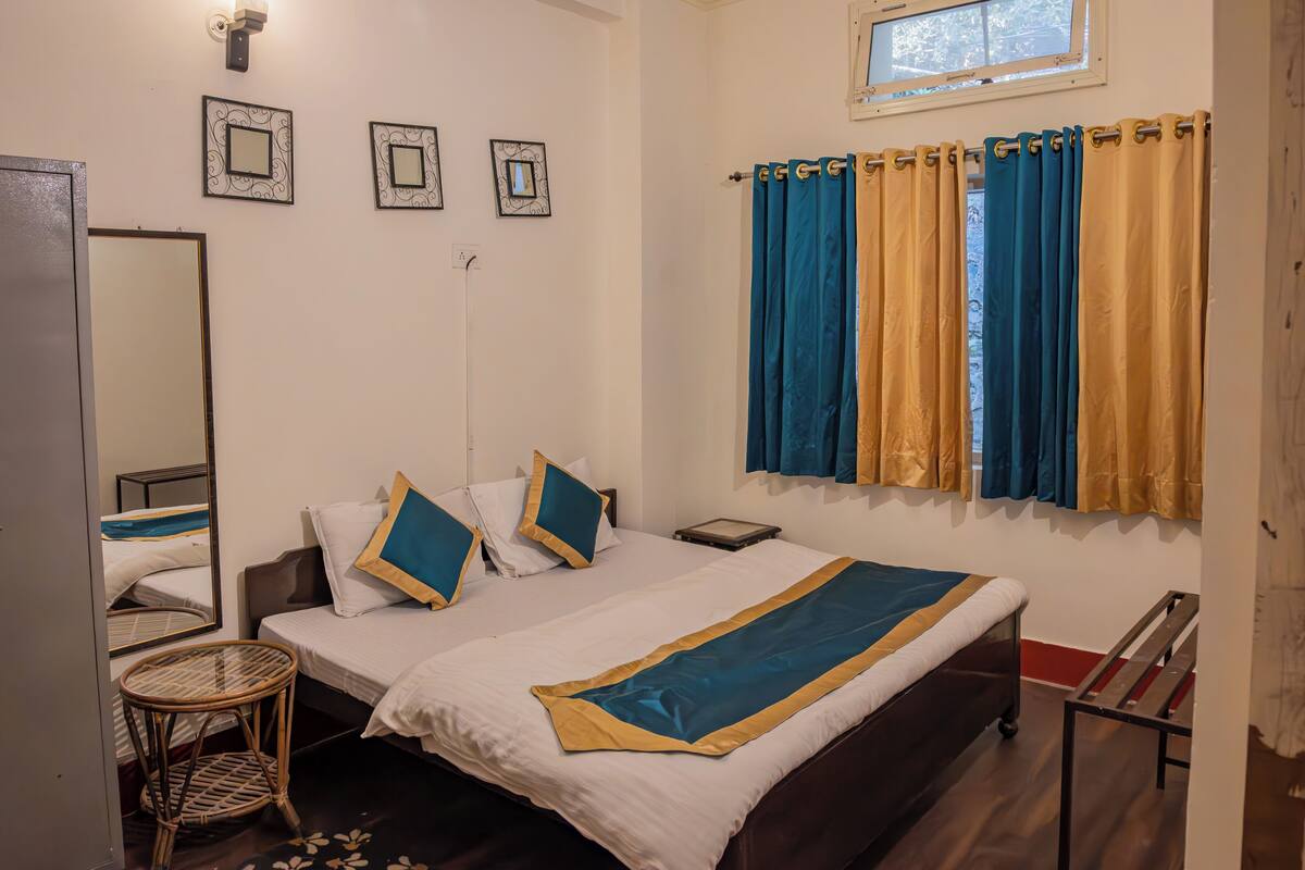 A bedroom with a bed, a bedside table, a small round table, and a mirror.