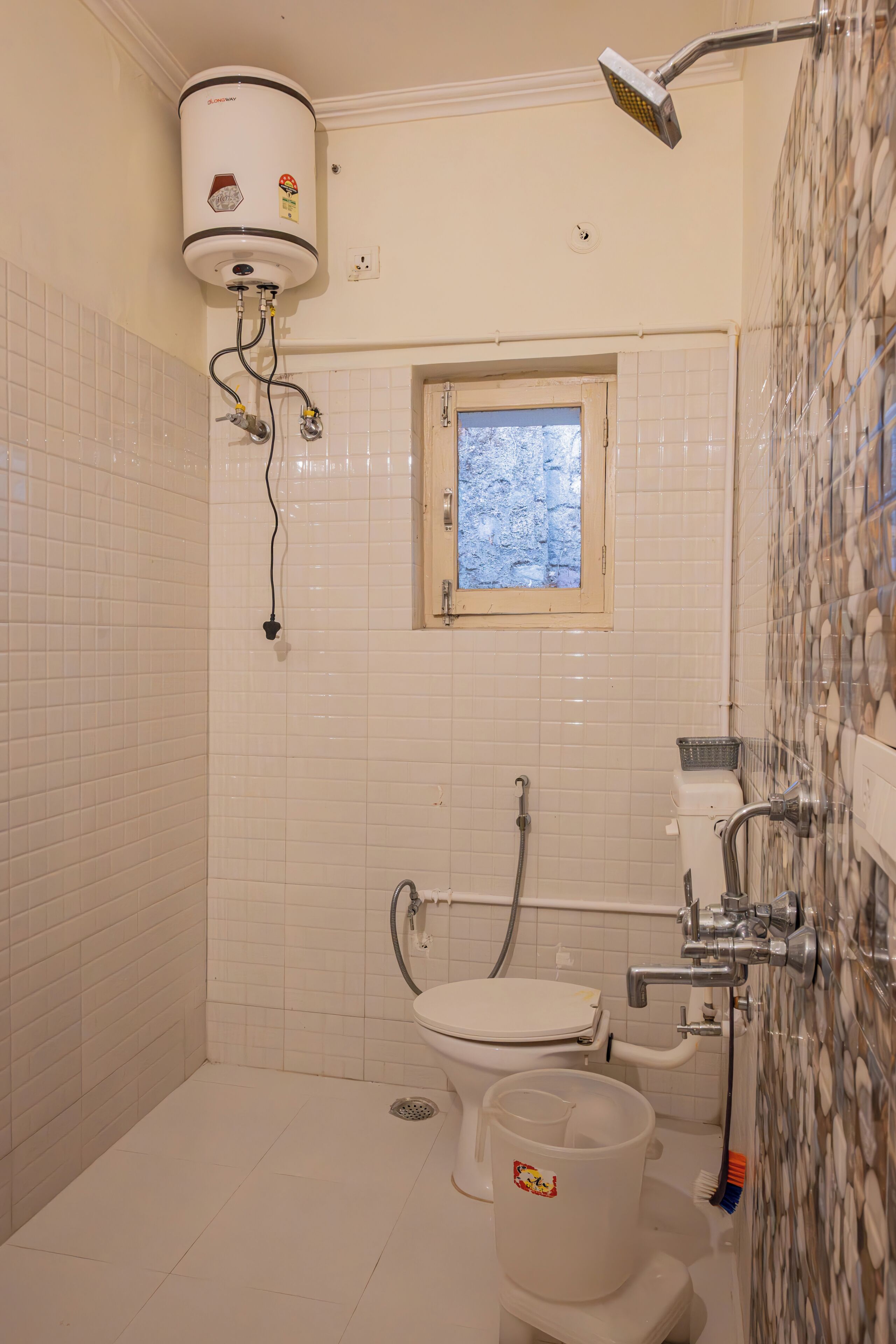 A bathroom with a toilet, a window, a shower, and a water heater.