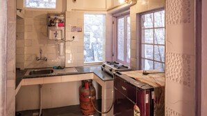 A compact kitchen with a gas stove, sink, and a gas cylinder.
