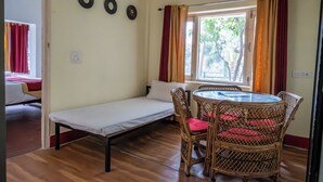 A room with a single bed, a small table with chairs, and a window with curtains.