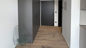 A narrow hallway with a metal chair, a door, and a vent on the ceiling. - New Age Boardinghaus Bad Rappenau (Bad Rappenau)