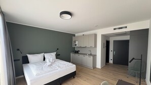 A modern hotel room with a bed, a small kitchenette, a dining area, and a separate bathroom. - New Age Boardinghaus Bad Rappenau (Bad Rappenau)