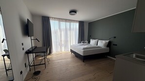 A modern hotel room with a bed, a desk, and a kitchenette. - New Age Boardinghaus Bad Rappenau (Bad Rappenau)