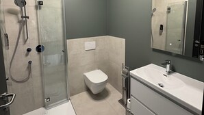 A modern bathroom with a glass shower enclosure, a white toilet, and a vanity with a mirror. - New Age Boardinghaus Bad Rappenau (Bad Rappenau)