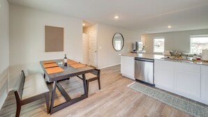 Una cocina moderna con comedor, armarios blancos y un ventanal que proporciona luz natural.