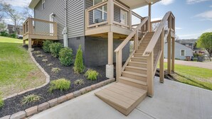 Een huis met twee verdiepingen, een houten terras, een trap en een kleine tuin.