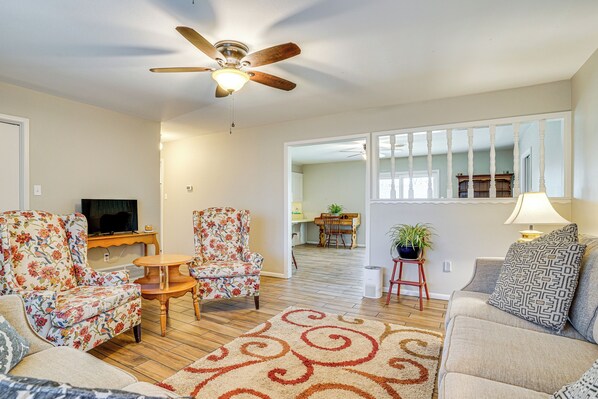 A living room with a ceiling fan, floral armchairs, a sofa, a TV, and a dining area in the background. - Family Friendly: Peaceful Home in Stamford! (Stamford)