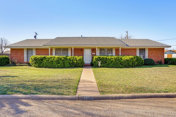 A single-story brick house with a front porch, a central door, and a small front yard with trimmed bushes. - Family Friendly: Peaceful Home in Stamford! (Stamford)