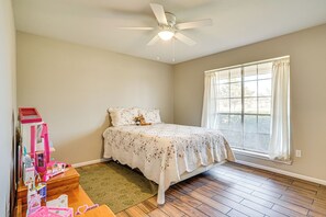 A bedroom with a bed, a window with curtains, a ceiling fan, and a small table with toys. - Family Friendly: Peaceful Home in Stamford! (Stamford)