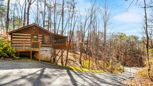 Eine rustikale Holzhütte mit einer Holzterrasse, umgeben von einem bewaldeten Gebiet.