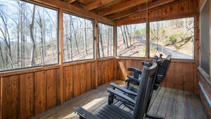 Eine Holzhütte mit Veranda, großen Fenstern und einer Schaukel.