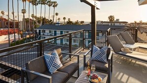 A rooftop terrace with a pool, lounge chairs, and a table with snacks and drinks.
