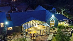 Une maison dotée d’une grande serre en verre, d’un patio couvert et d’un jardin bien entretenu.