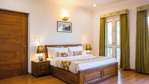 A neatly arranged bedroom with a wooden bed, bedside lamps, a framed picture on the wall, and green curtains on the windows. - Alaya Stays Captains Nest 3 BHK Retreat With Garden & Scenic Views (Kasauli)