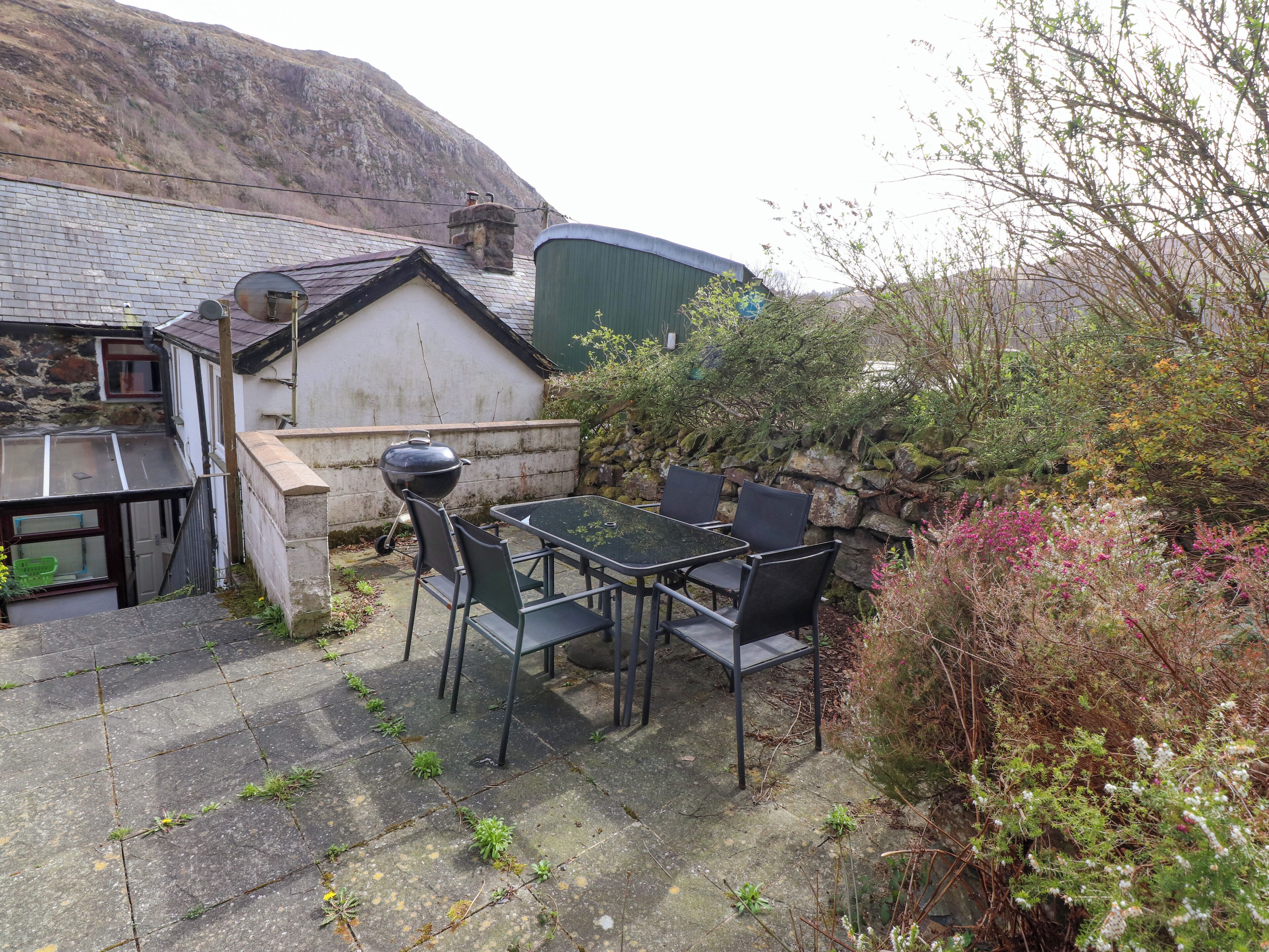 A patio with a table and chairs, a barbecue grill, and a stone wall.