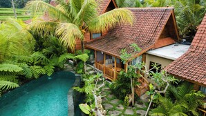 A bungalow with a tiled roof, surrounded by lush greenery and a swimming pool. - Edge of Ubud by GenuineHost (Ubud)