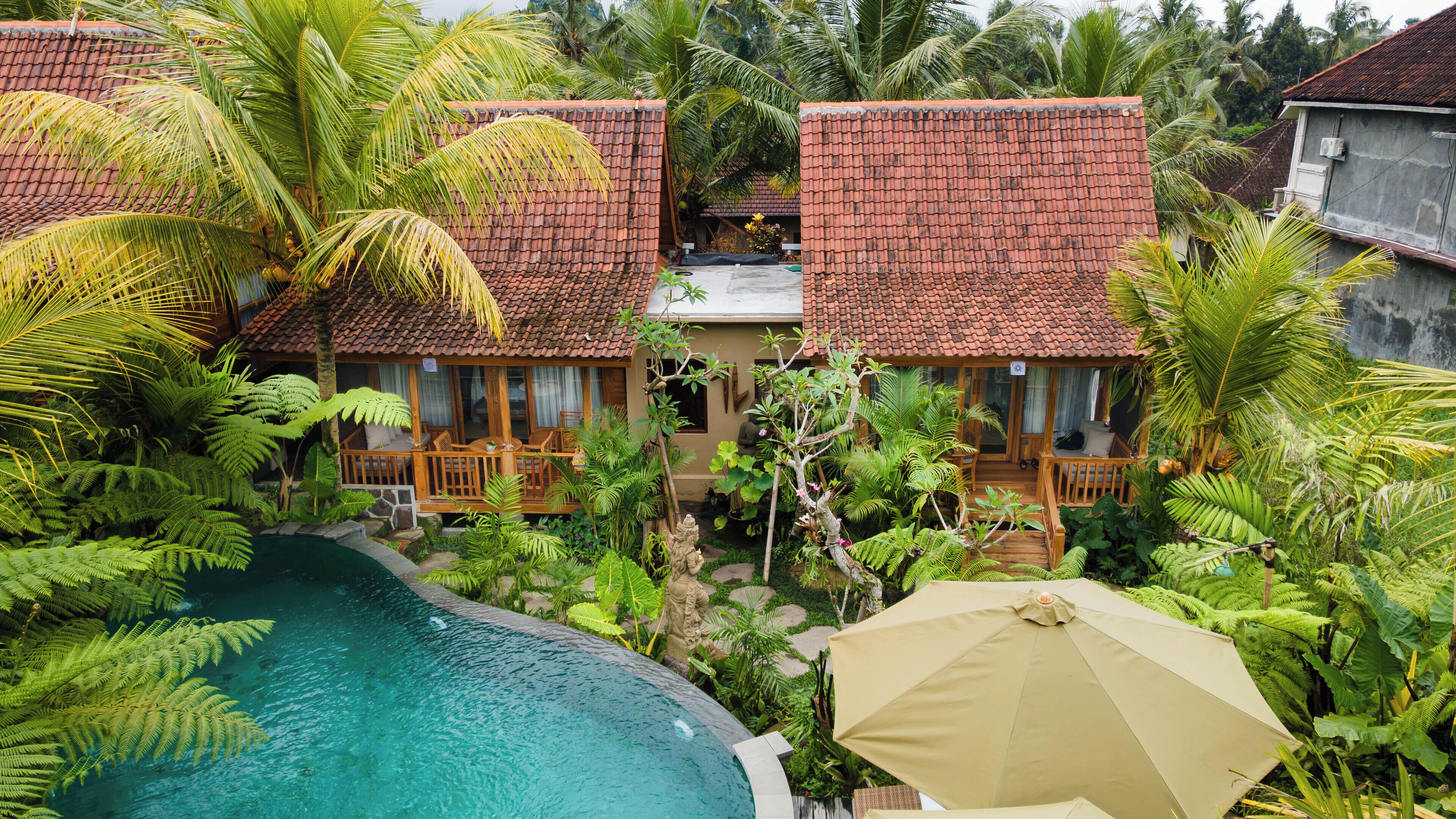 A resort with multiple bungalow-style buildings, a swimming pool, and lush tropical vegetation.