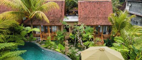 A resort with multiple bungalow-style buildings, a swimming pool, and lush tropical vegetation.