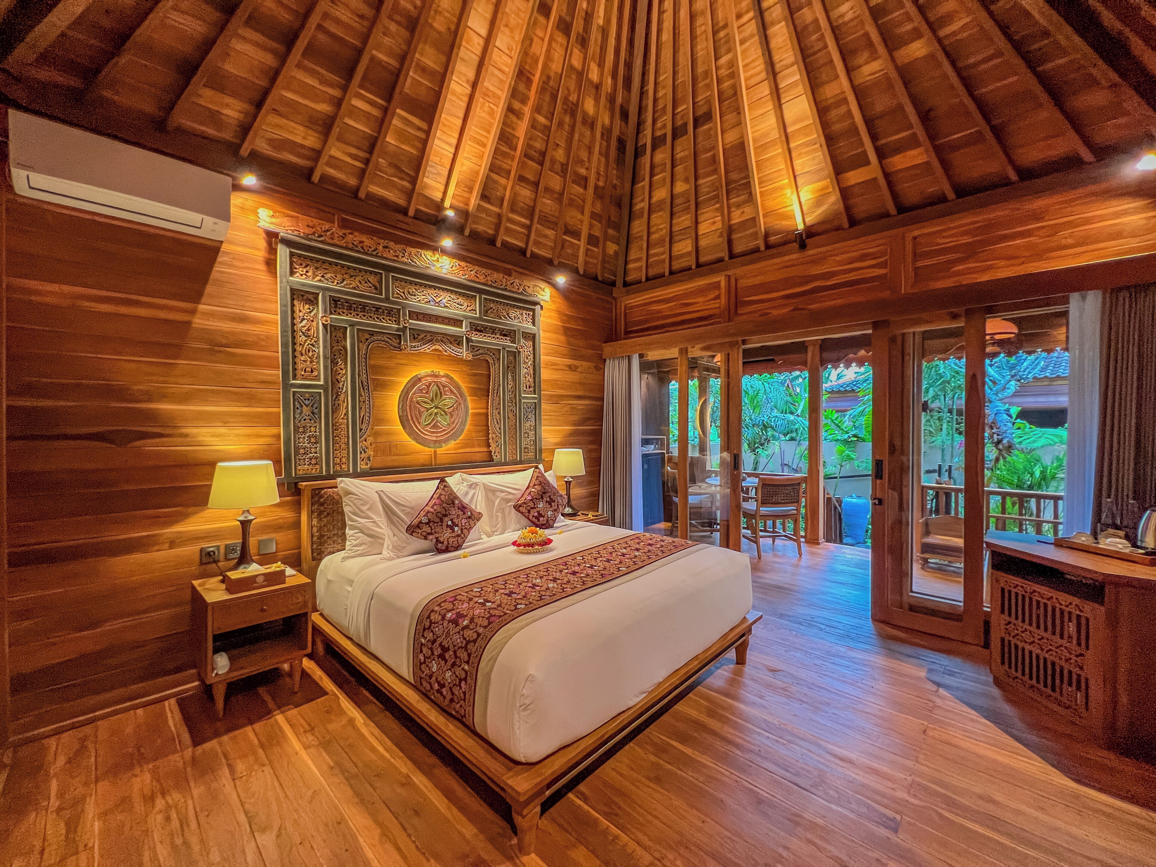 Quarto com decoração em madeira, com uma cama, mesas de cabeceira e um painel decorativo na parede.