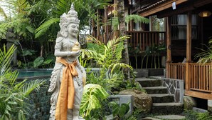 A statue in a garden with stone steps and tropical plants. - Edge of Ubud by GenuineHost (Ubud)