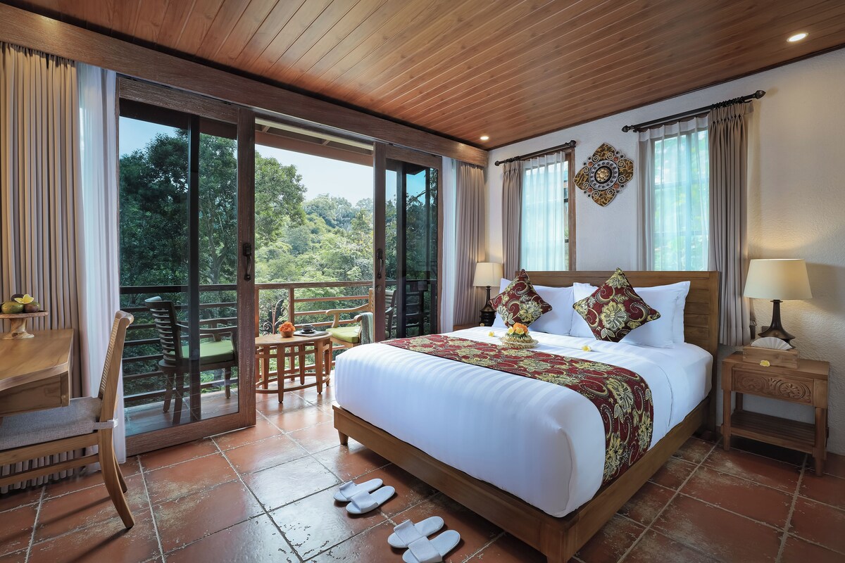 A spacious bedroom with a large bed, a wooden headboard, and a view of the outdoors.