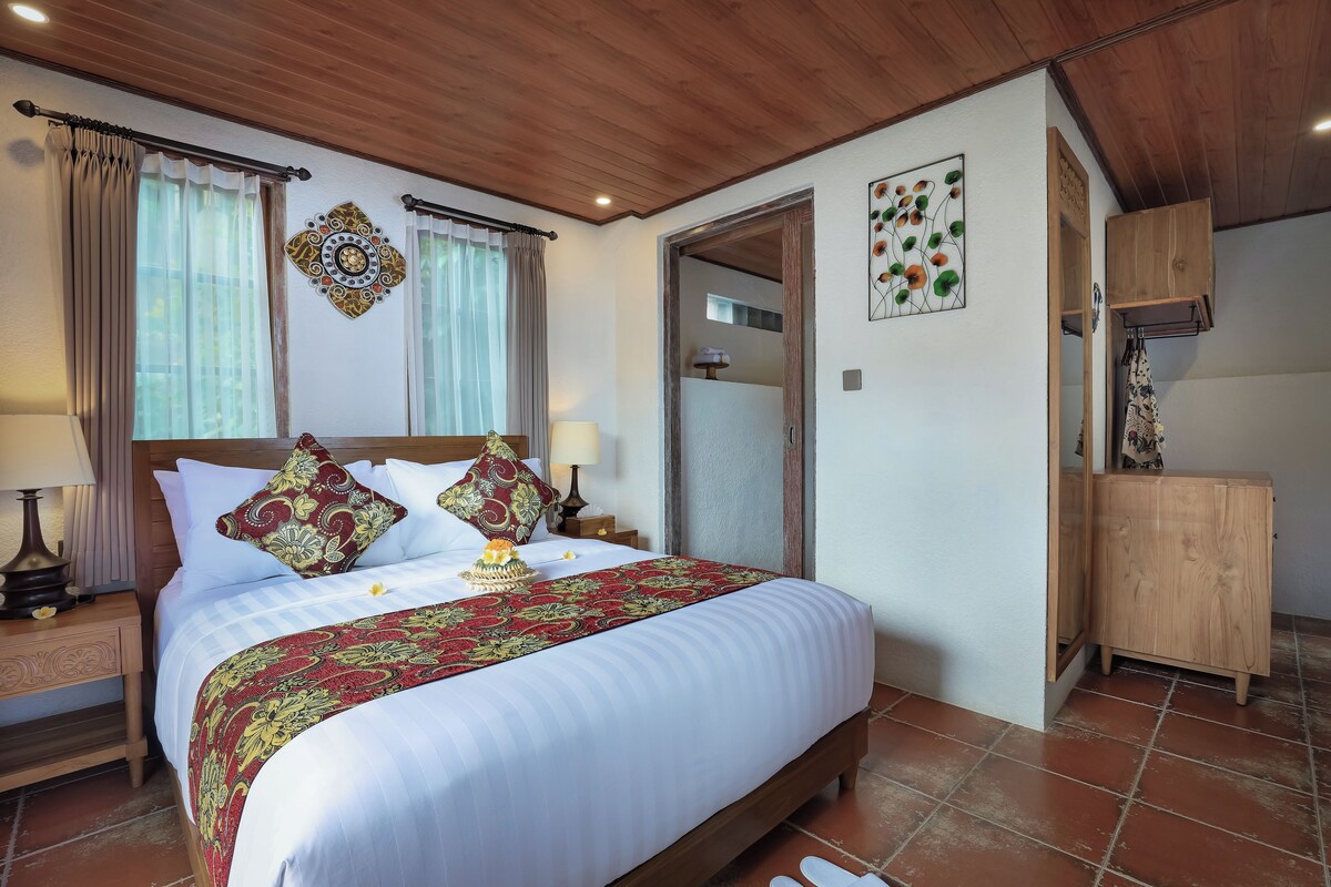 A neatly made bed with a patterned bedspread, a wooden headboard, and two bedside lamps.