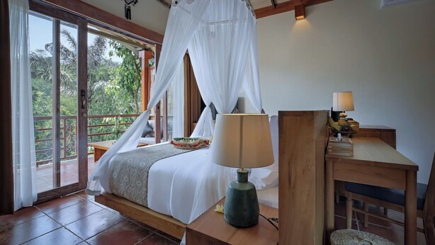 Un dormitorio con cama con dosel, una mesita de noche con lámpara y vistas al exterior.