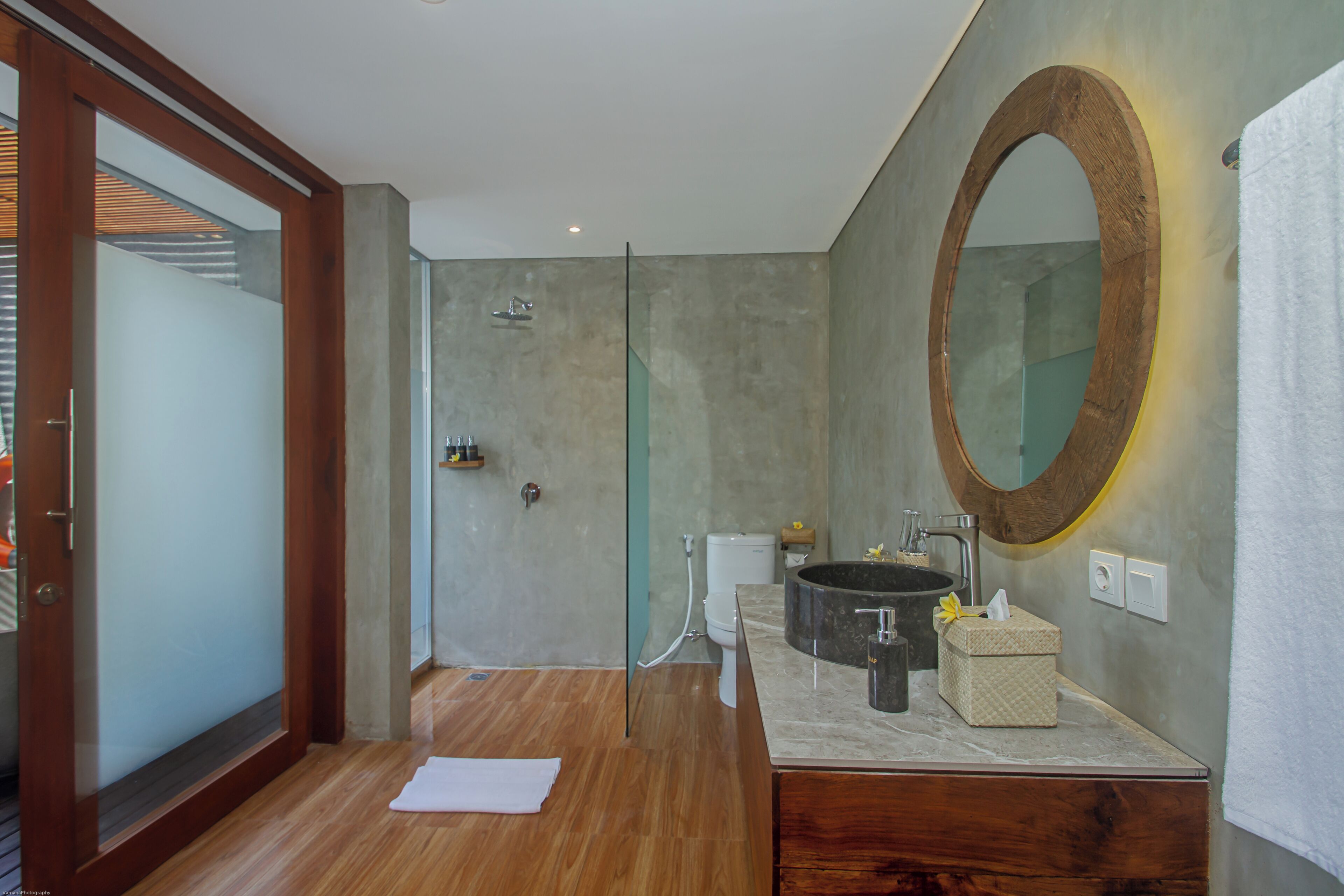 A modern bathroom with a wooden vanity, a large mirror, and a glass shower enclosure.