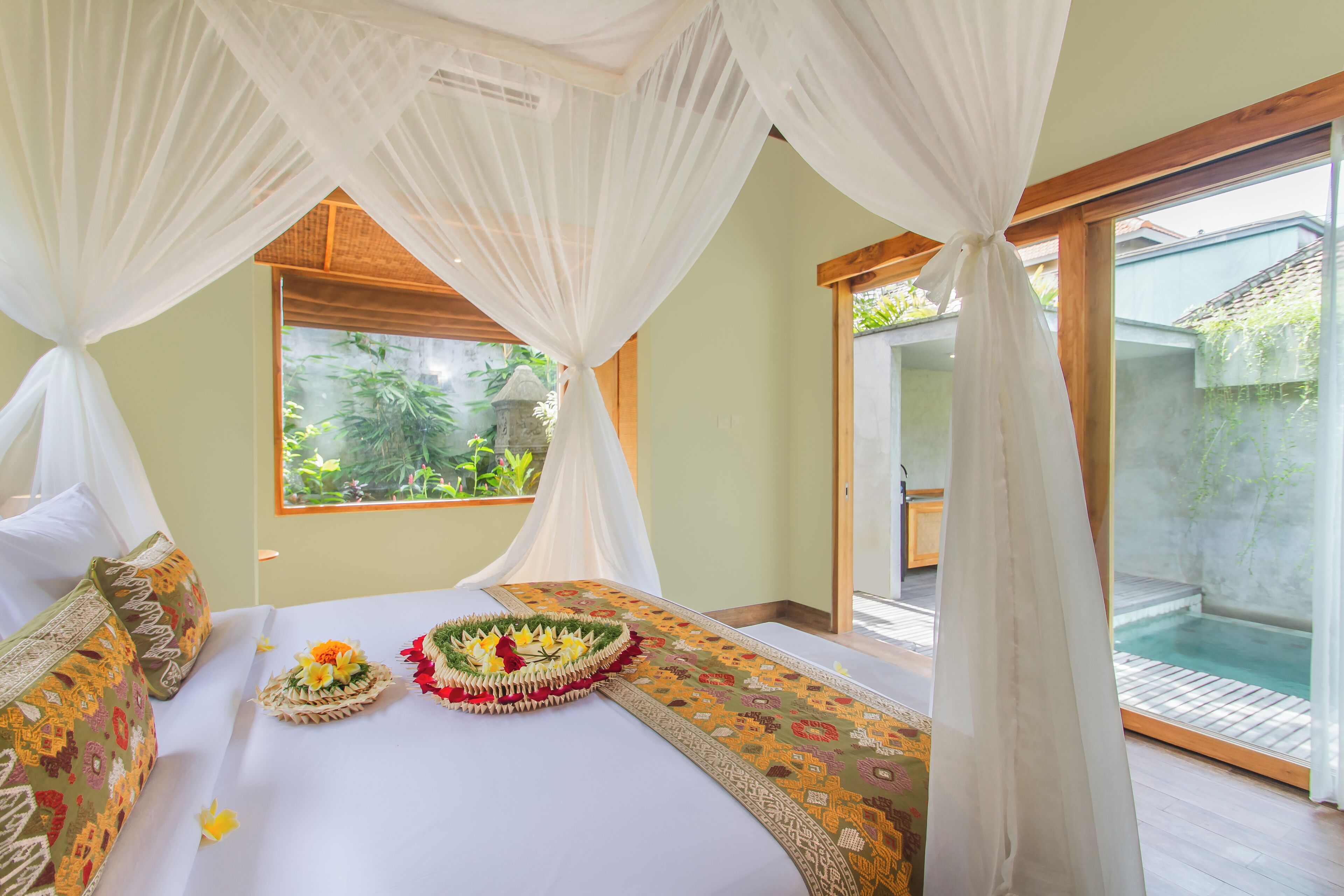 A bedroom with a bed, a window, and a view of a garden.