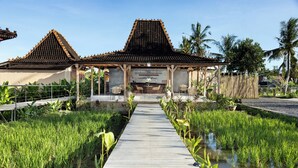 A traditional building with a tiled roof and a wooden walkway leading to a covered area with seating.