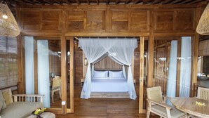 A wooden room with a bed, two chairs, a small table, and a hanging light fixture.