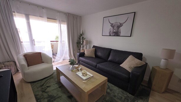 A living room with a sofa, armchair, coffee table, and a ceiling fan.