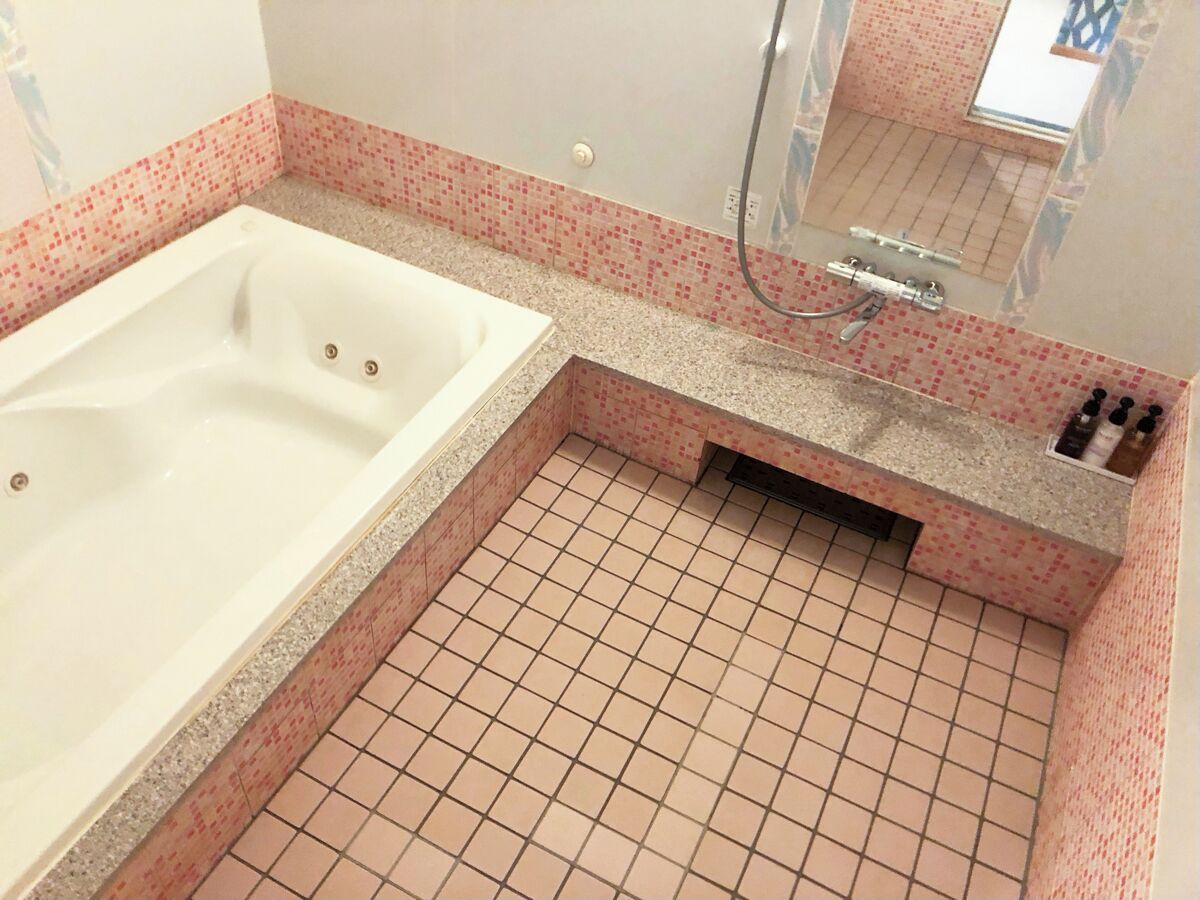 Une salle de bain avec une baignoire, un espace douche et un carrelage au sol.