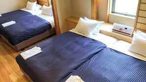 Zwei Einzelbetten mit dunkelblauer Bettwäsche, weißen Kissen und einem Nachttisch mit Bedienfeld.