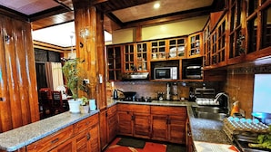 Una cocina con armarios de madera, microondas y pileta.