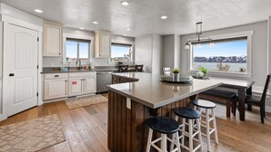 A modern kitchen with a central island, bar stools, and a view of a lake.