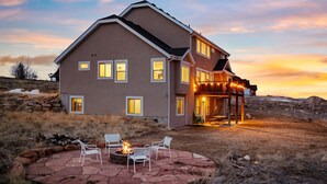 A two-story house with a fire pit and outdoor seating area.