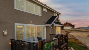 A house with a deck, a covered outdoor seating area, and a view of the landscape.
