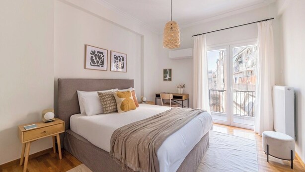 A bedroom with a bed, bedside table, lamp, and a view of the outside. - Modern Athenian Nest near Kallimarmaro Stadium (Athina)