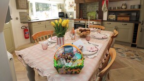 A kitchen with a dining table set for a meal, a fire extinguisher, and a window with curtains. - The Museum (Alston)
