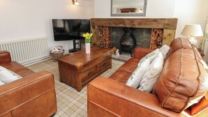 A living room with a fireplace, sofa, television, and a wooden coffee table. - The Museum (Alston)