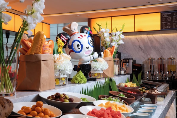 A buffet setup with various food items and a decorative chef figurine. - Hampton by Hilton Shenzhen Baoan Xinan (Shenzhen)