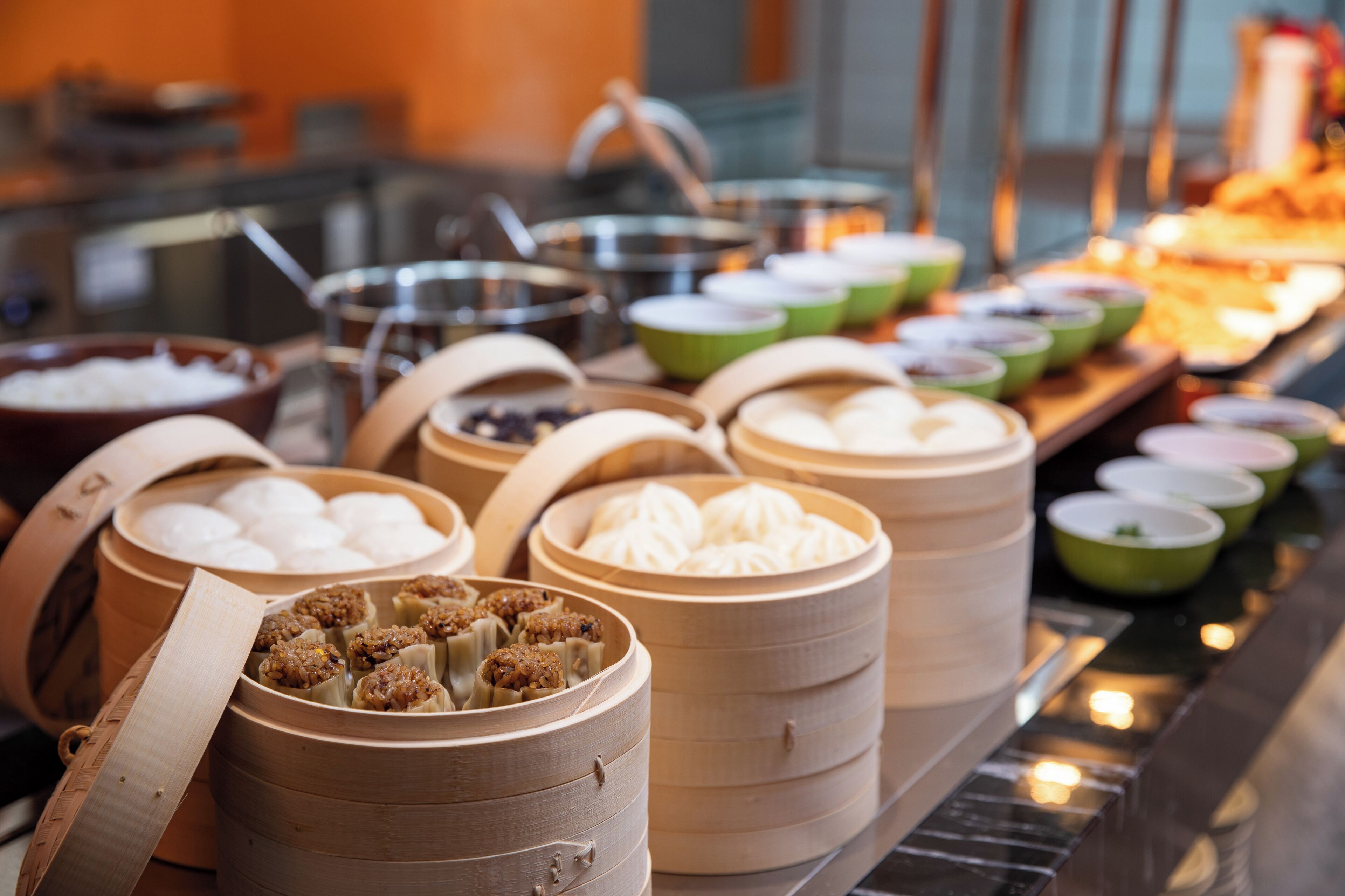 Un buffet proposant divers plats, notamment des raviolis et d’autres mets, présentés dans des paniers à vapeur en bambou.