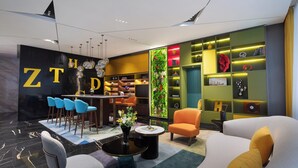 Una hall moderna di un hotel con zona bar, posti a sedere e una parete verde con giardino verticale.