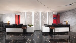 Un'accoglienza moderna con pavimento in marmo, due scrivanie della reception e illuminazione decorativa.