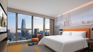 Una camera d'albergo moderna con un letto grande, una sedia, una scrivania e vista sulla città.