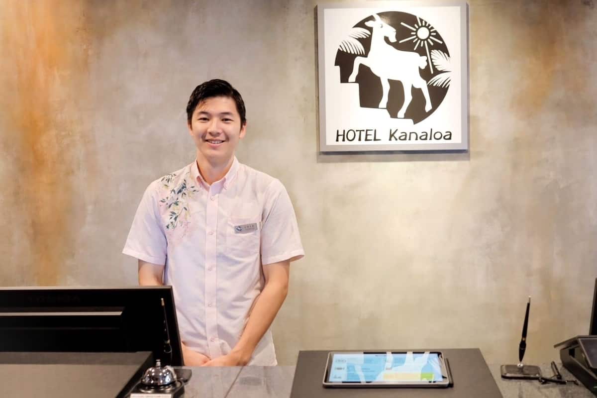 Una recepción de hotel con una tableta digital, un timbre tradicional y una estación de carga para teléfonos inteligentes.