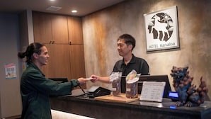 A hotel reception desk with a sign for HOTEL Kanaloa, a wooden cabinet, and a decorative statue. - HOTEL KANALOA (Tokashiki)