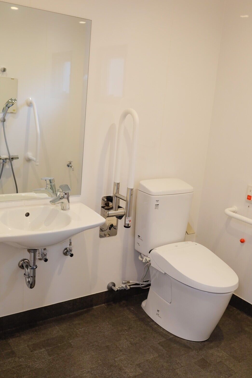 Une salle de bain moderne avec un lavabo, des toilettes et une douche, le tout de couleur blanche.
