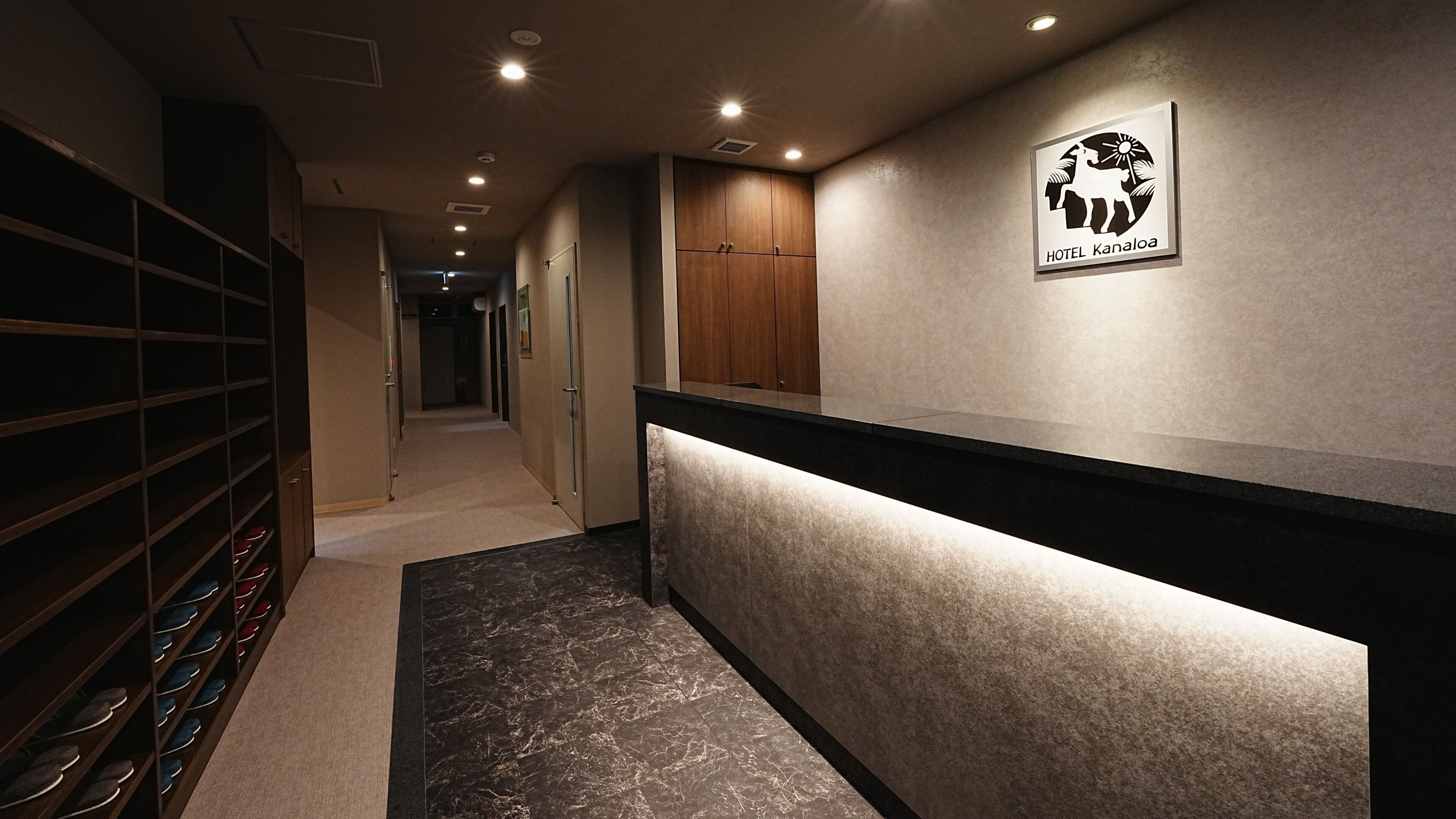 A hotel reception area with a counter, shoe rack, and a sign for HOTEL KANALOA.